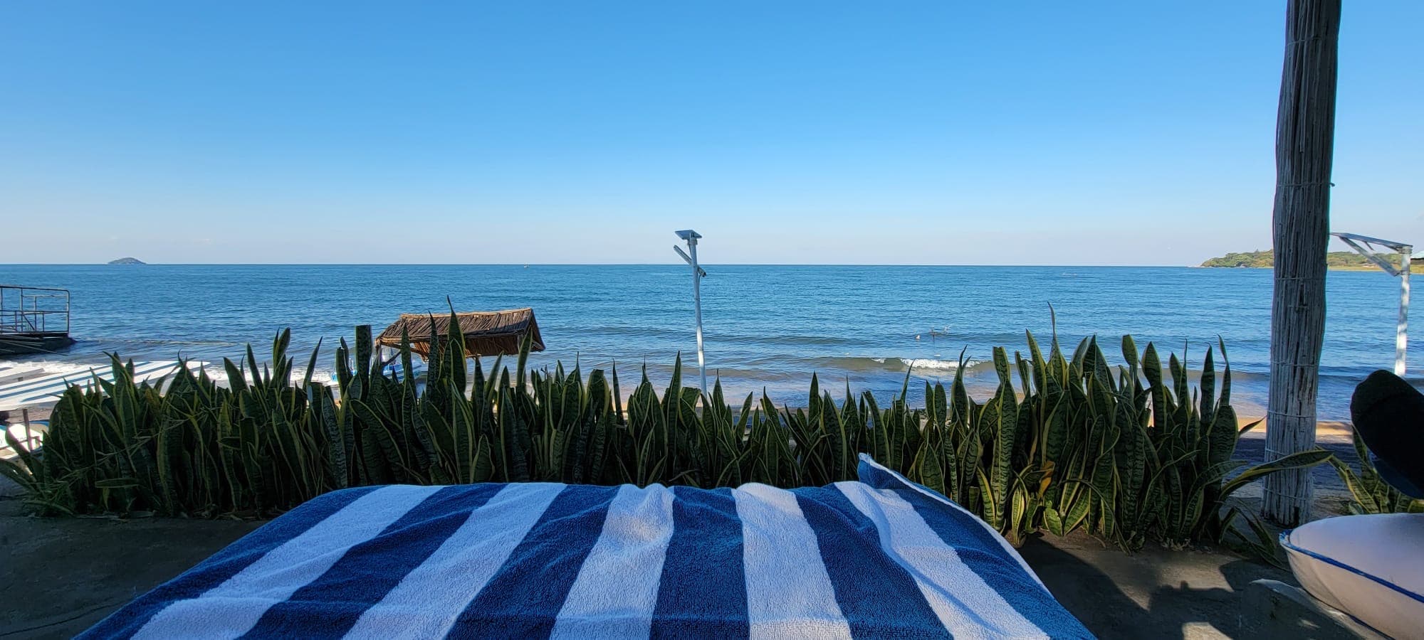 Relaxing beachfront view of Lake Malawi with striped towel, and clear blue water