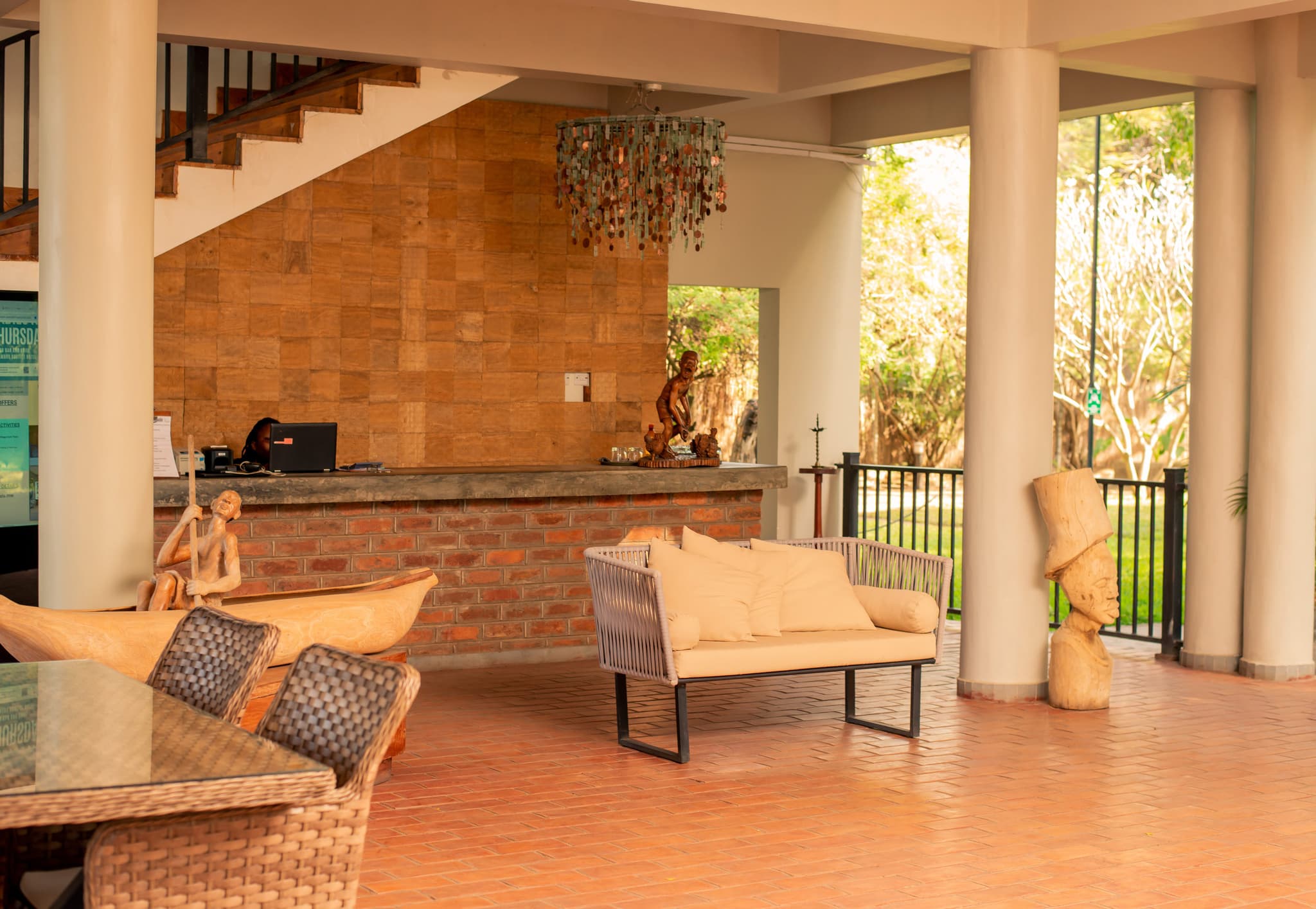 hotel reception area with natural brick and wood décor, comfortable seating, and local wooden sculptures